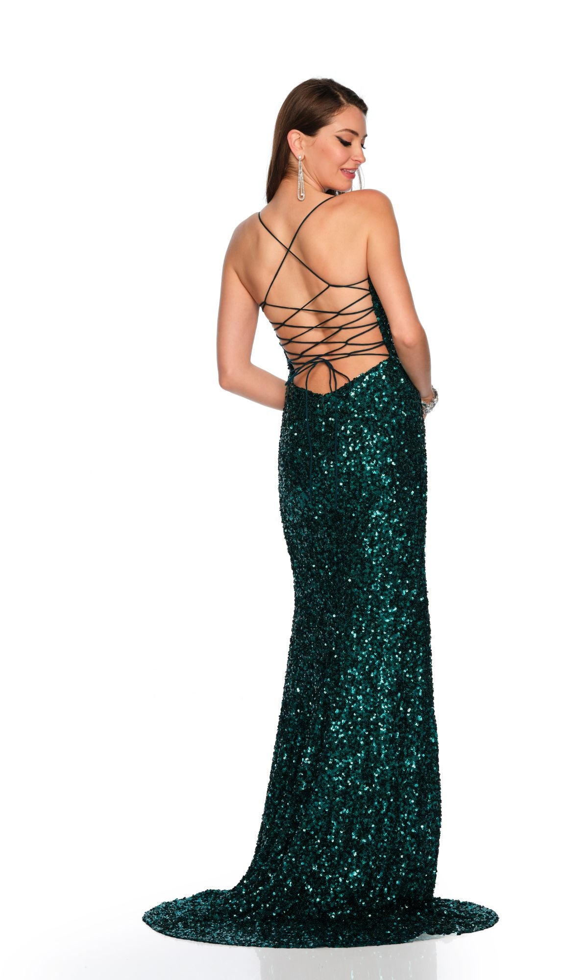 Woman in a dark green Dave & Johnny 11471 tight long sequin prom dress with a lace-up open back, standing and looking over her shoulder against a white background.